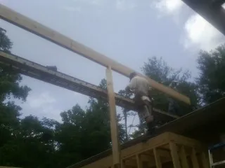 Carpenter setting a ridge beam over a new addition frame — Ice Dam Removal by Roofing Brothers in Bozeman