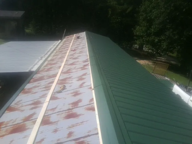 Old rusted panels beside newly installed green metal roofing — Wind Damage Roof Repair by Roofing Brothers in Bozeman