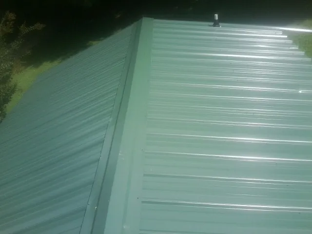 New green metal panels meeting at the ridge of a roof — Flat Roof Repair work by our crew in Bozeman