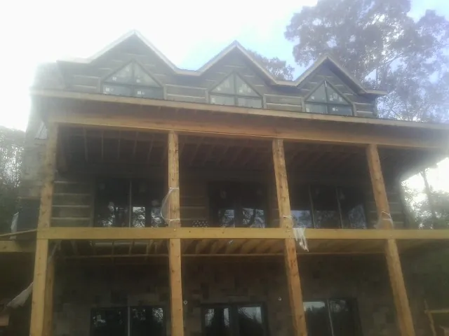 Dormers and porch framing on a large log home under construction — Roof Coating work by our crew in Bozeman