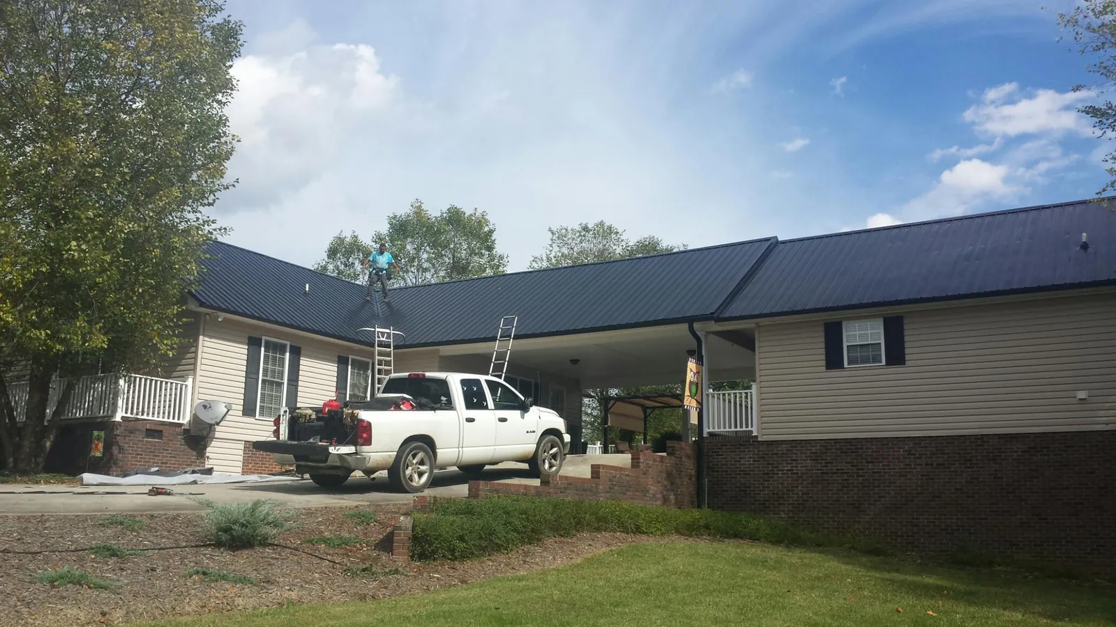 Black metal roof over a home and attached breezeway with ladders set in Bozeman