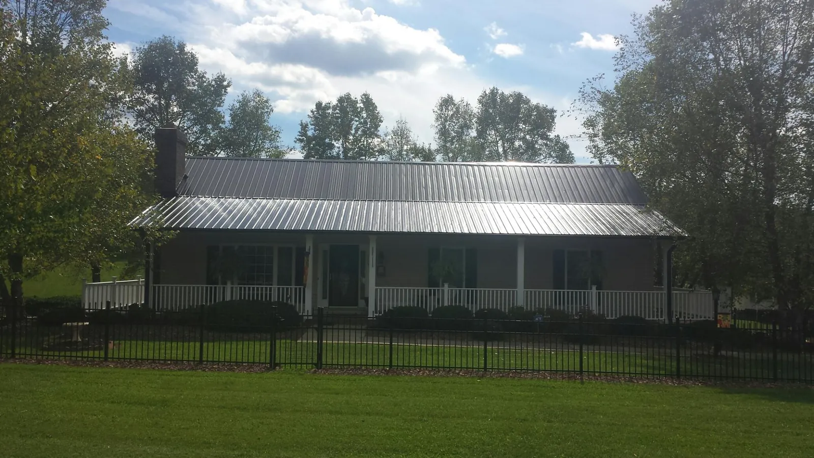 Gray metal roof on a brick ranch with a full width front porch — Gutter Guard Installation work by our crew in Bozeman